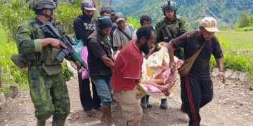 Anggota TNI dan warga mengevakuasi korban luka-luka akibat diserang TPNPB, di distrik Anggruk, kabupaten Yahukimo, Papua Pegunungan, Minggu (23/03/2025)